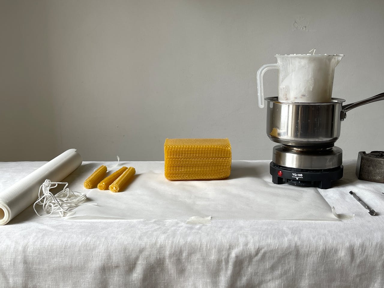 Flat lay of beeswax candle making tools and materials on a table.